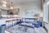 Modern open-concept living room and kitchen with a chic blue sofa, stylish pendant lights, and breakfast bar seating.