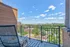 Inviting balcony view of a vibrant cityscape and lush greenery, complete with a stylish chair for ultimate relaxation.