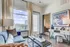 Bright living room with modern decor, featuring a cozy blue sofa, stylish coffee table, and a stunning city view through large windows.