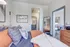 Cozy bedroom with modern decor, abundant pillows, and a warm ambiance, leading to a chic bathroom and stylish kitchen.