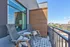 Charming balcony with chic wicker chairs and a cozy rug offering a stunning city view.