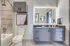 Elegant bathroom featuring modern fixtures, illuminated mirror, and stylish gray cabinets with a sleek countertop.