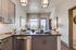 Modern kitchen with sleek cabinetry, stylish lighting, and a captivating city view through large windows.