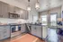 Bright and modern kitchen featuring sleek gray cabinets, stainless steel appliances, and elegant pendant lighting, with a stunning view through large windows.