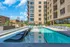 Luxurious apartment exterior featuring a stunning outdoor pool with sleek lounges, surrounded by modern architecture and city skyline views.