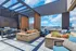 Sophisticated rooftop terrace with stylish blue seating, vibrant floral arrangements, and stunning cityscape views under a clear blue sky.