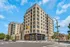Modern apartment building with spacious balconies and elegant design on a sunny street corner.