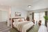 Bright and elegant bedroom with contemporary decor, large bed, and cozy seating area by sunlit windows.