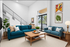 Modern living room with stylish blue sofas, vibrant artwork, and large windows offering natural light and serene outdoor views.