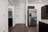 Modern apartment entrance with sleek wood flooring, elegant granite countertops, and stainless steel refrigerator in a stylish kitchen setting.