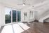 Bright, modern living space with floor-to-ceiling windows, sleek ceiling fan, and dark hardwood floors, offering a stylish and inviting atmosphere.