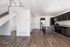 Modern open-concept kitchen and living area with sleek dark cabinetry, stainless steel appliances, and elegant wood flooring.