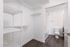 Modern apartment showcasing a spacious walk-in closet with sleek shelving leading into a bright, pristine bathroom.