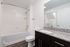 Elegant bathroom with granite countertop, a large mirror, and a modern bathtub in a bright, spacious setting.