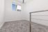 Bright and modern room with fresh white walls, plush carpet, and a sleek metal railing, offering a serene view through the window.