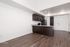 Contemporary kitchen with sleek dark wood cabinets, polished granite countertops, and modern stainless steel appliances, set against elegant wood flooring.