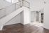 Bright, modern apartment interior featuring sleek hardwood floors, a stylish metal railing staircase, and large sliding glass doors opening to a private balcony.