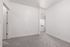 Bright and modern empty room with pristine white walls and plush gray carpeting, featuring a large window that invites natural light.
