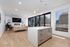 Contemporary open-plan living area with sleek kitchen island, cozy seating, and expansive windows overlooking lush greenery.
