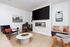 Contemporary living room with elegant wood flooring, stylish seating, wall art, large flat-screen TV, and modern fireplace.