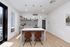 Modern kitchen with sleek design featuring pendant lighting, a central island with brown chairs, and contemporary decor.