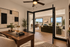 Elegant modern office space with a wooden desk, artistic decor, and large windows opening into a luxurious living area with scenic views.
