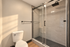 Modern bathroom featuring elegant glass shower doors, sleek tiled walls, and a stylish rain showerhead.