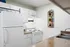 Modern kitchen with white cabinets and appliances, featuring a sleek countertop and a stylish wall-mounted magazine rack.