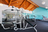 Modern gym with sleek exercise equipment, vaulted wooden ceiling, and vibrant turquoise walls for an invigorating workout experience.