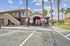 Inviting apartment complex entrance with festive red and white balloons, palm tree landscaping, and sunny skies.