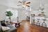 Inviting living area with sleek wood floors, modern ceiling fans, and an elegant open-plan design featuring comfortable seating and a chic breakfast bar.