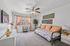 Bright and inviting guest room with elegant decor, featuring a cozy daybed adorned with patterned pillows, a lush indoor plant, and stylish orange curtains framing a sunlit window view.
