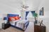 Inviting bedroom with a plush blue headboard, vibrant orange accent pillows, and elegant blue curtains, creating a cozy and stylish ambiance.