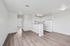 Bright and modern open-plan kitchen and living space with sleek white cabinetry and elegant wood flooring.