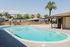 Inviting outdoor pool area with crystal-clear water, surrounded by picturesque palm trees and mountains in the background, offering a serene and relaxing atmosphere.