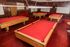 Inviting game room featuring multiple red-felt pool tables, perfect for entertainment and leisure activities.