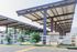 Modern covered parking area with solar panel roofs at Desert Palms MHP, surrounded by neatly arranged planters with lush greenery.