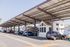 Modern covered parking area featuring RVs and a tiny home under a sleek solar roof, offering sustainable living solutions.