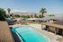 Charming residential area featuring a sparkling swimming pool, surrounded by palm trees and scenic mountain views, perfect for relaxed living.