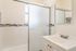 Modern bathroom featuring a sleek glass shower, elegant white vanity, and stylish tile accents.