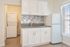 Bright and modern kitchen featuring sleek white cabinets, elegant backsplash, and an in-unit washer and dryer for convenient living.