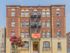 Charming Tudor Apartment building with classic brick facade and inviting entrance, highlighted by vibrant floral landscaping.
