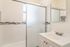 Elegant and modern bathroom featuring sleek white tiles, a stylish mosaic accent, and a frosted glass shower door.