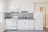 Contemporary kitchen with sleek white cabinetry, modern appliances, and a stylish tiled backsplash.
