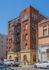 Charming vintage brick apartment building with unique architectural details and fire escape, set against a clear blue sky.
