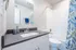 Modern bathroom featuring sleek white cabinetry, polished countertop, and an elegant shower with a vibrant floral curtain.