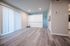 Spacious living area with elegant laminate flooring and modern sliding door, featuring bright, natural lighting.