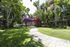 Lush garden pathway adorned with vibrant flowers and tropical greenery, leading to a luxurious apartment complex.