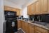 Charming kitchen with sleek black appliances, elegant wooden cabinets, and a granite countertop, ideal for culinary creativity.