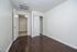 Bright, minimalistic room with fresh white walls, sleek dark hardwood flooring, and spacious closet.
